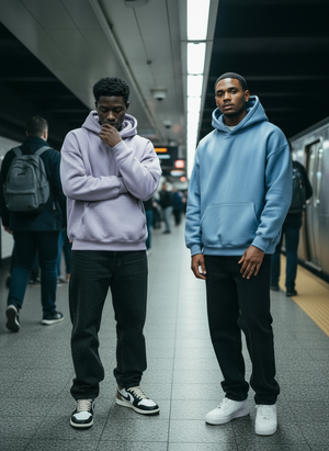 Two VALERO Legacy Hoodies in lilac and light blue, worn on a subway platform